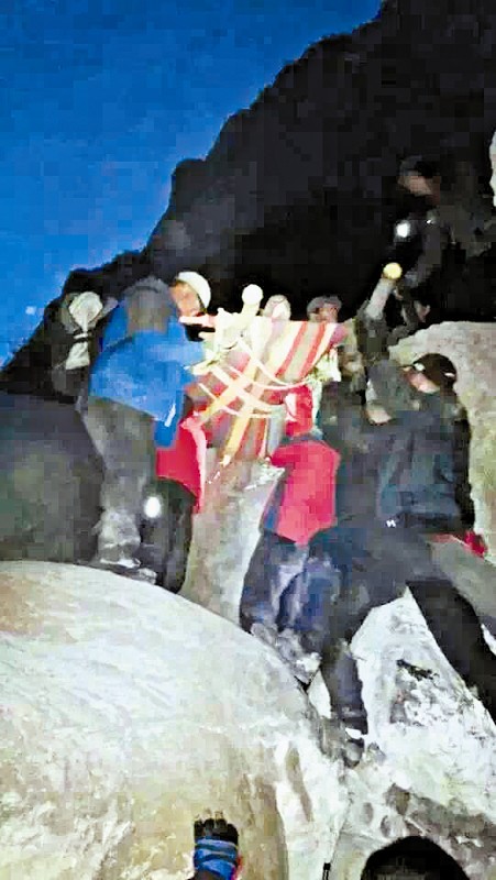 救援隊員用自制的簡易擔架抬傷者。